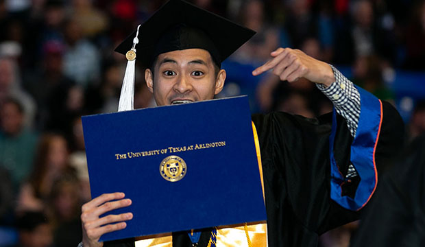 Graduate pointing at his new diploma.