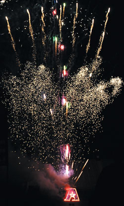 fireworks shoot out of a lighted logo